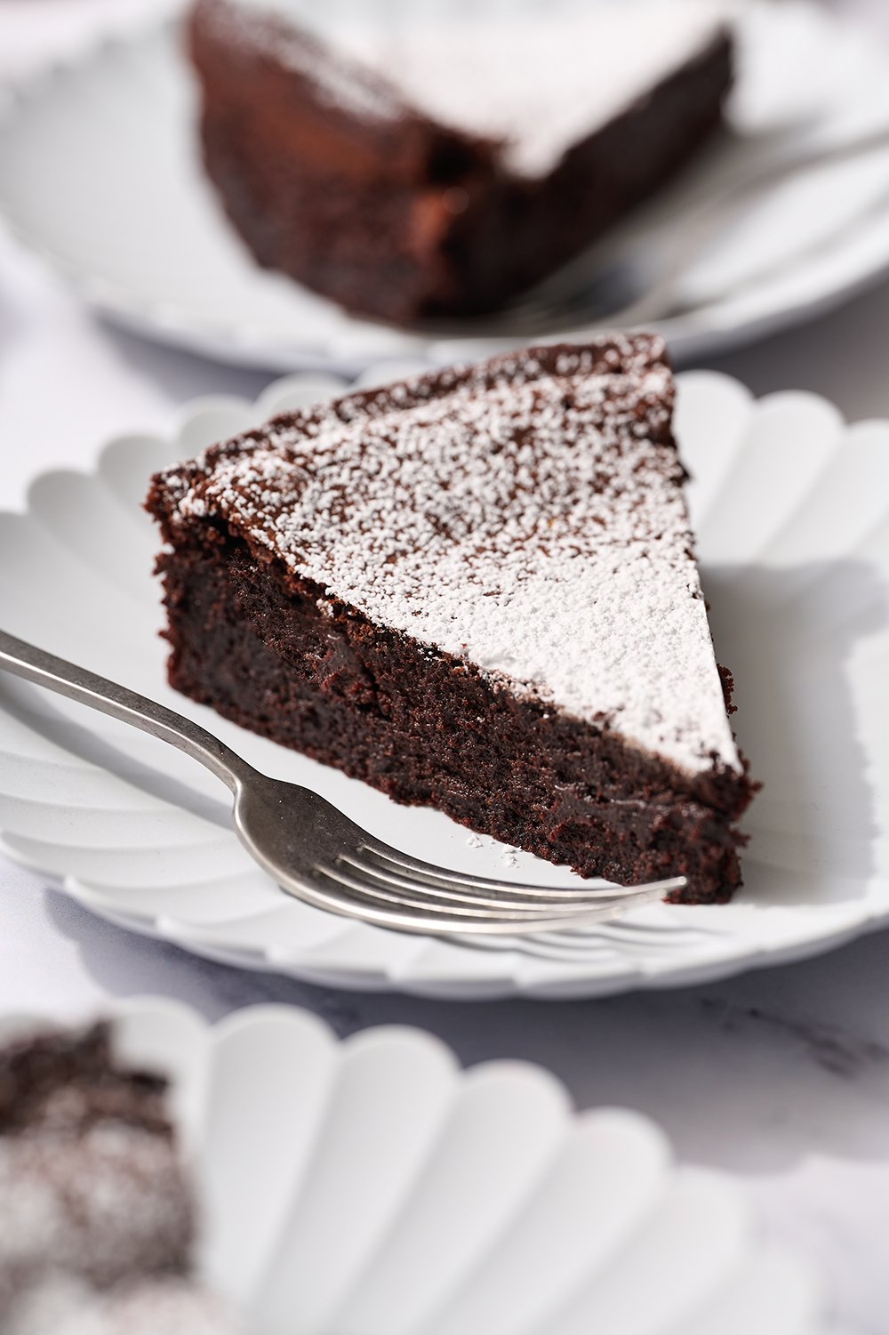 a fudgy slice of flourless chocolate cake on a plate.