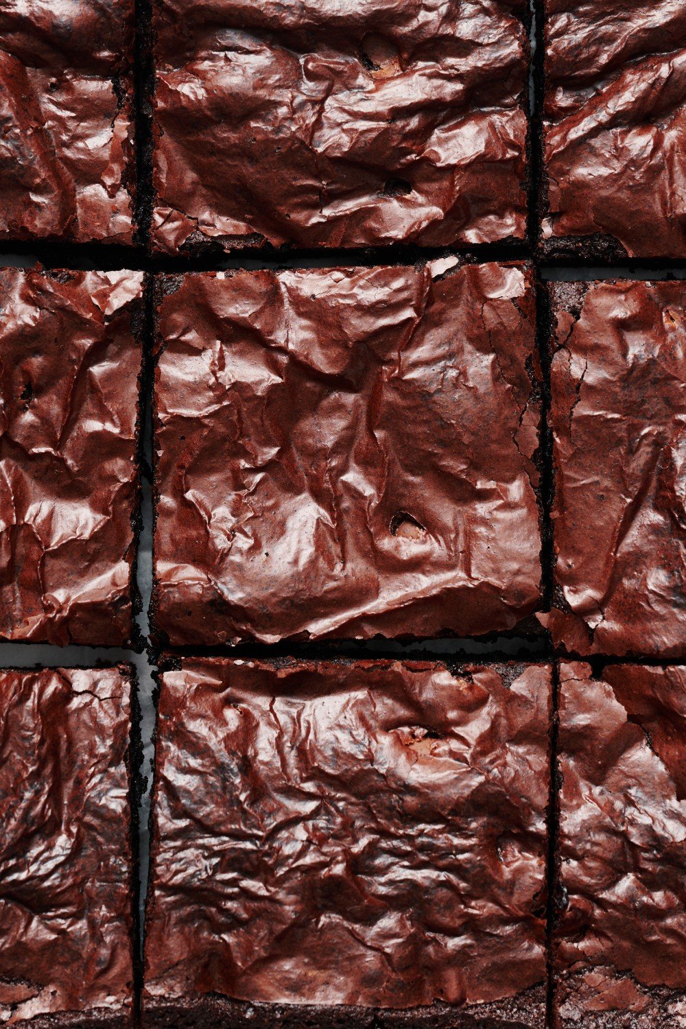 a whole pan of baked sliced chocolate brownies from above, showing their shiny thin crust. 