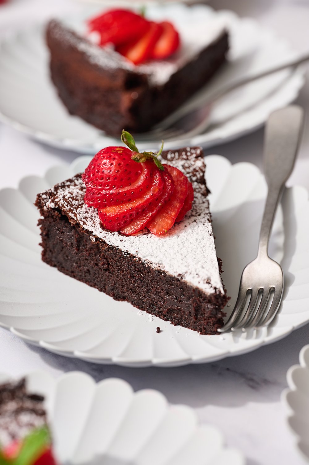 a slice of cake on a white plate with a strawberry on top.