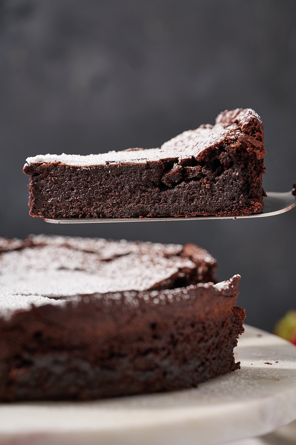 a slice of flourless chocolate cake being lifted from the cake to serve.