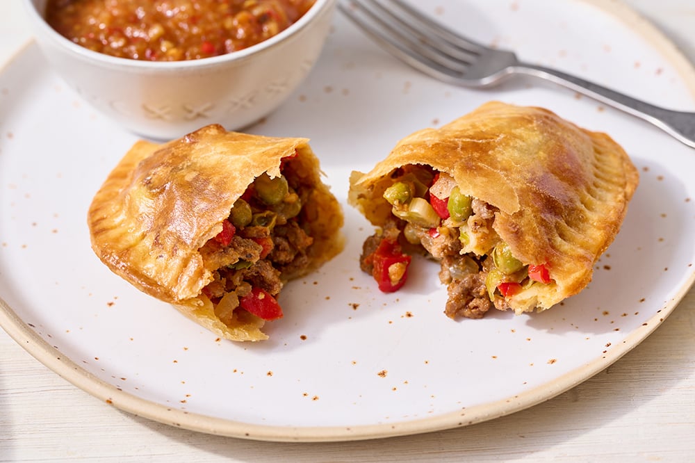 beef empanada on a plate with some salsa for dipping.