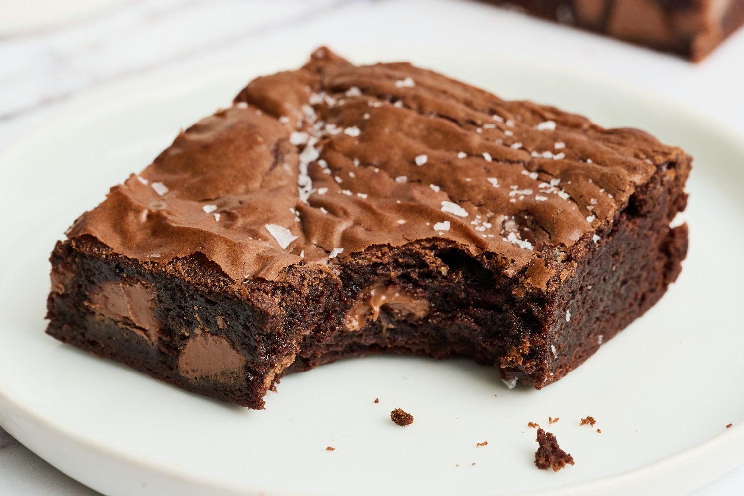 a brownie slice on a white plate, ready to serve.