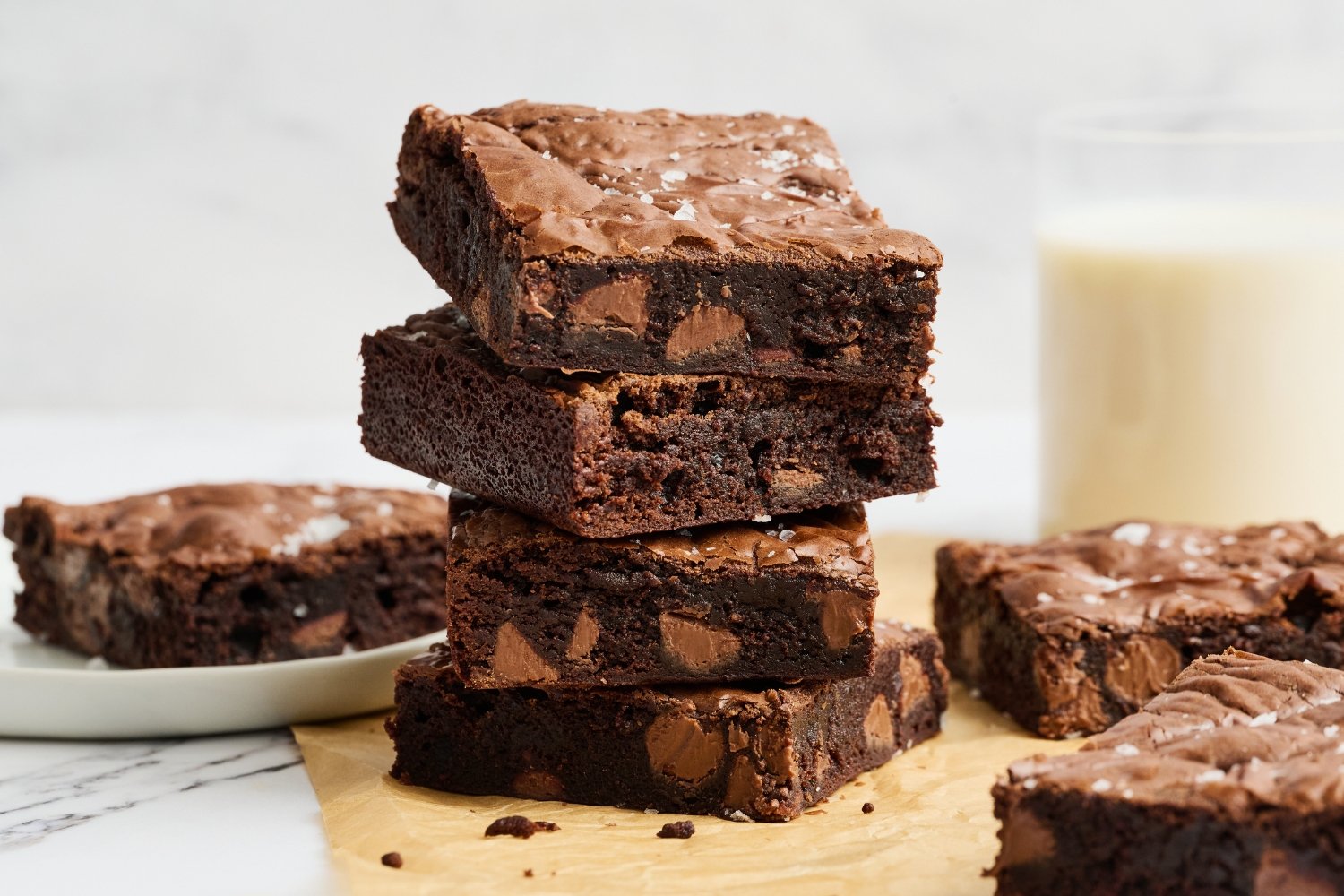 a stack of Malted Brownies with a glass of milk in the background. 