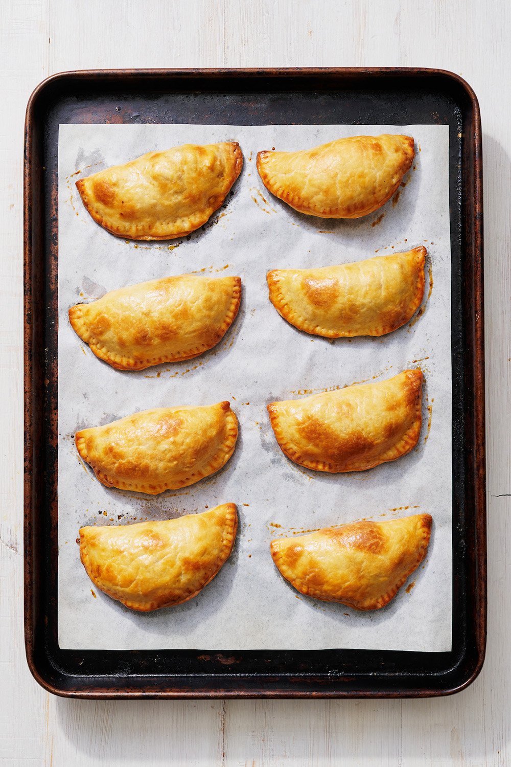 baked empanadas on a rimmed baking sheet, fresh out of the oven.