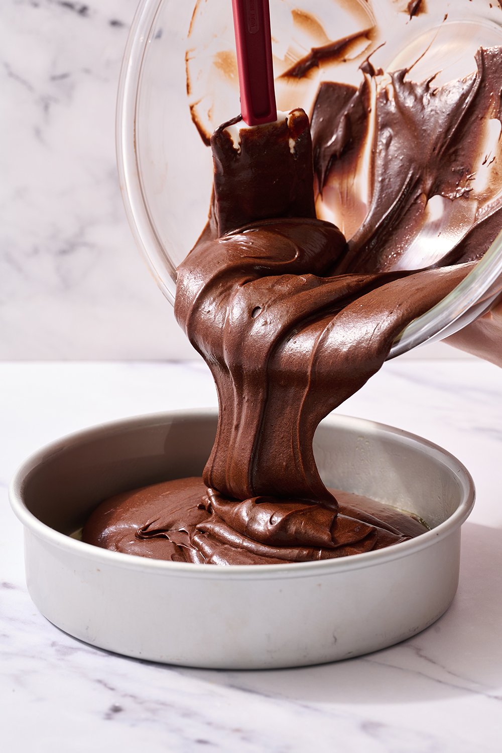 the batter being poured into the cake pan.