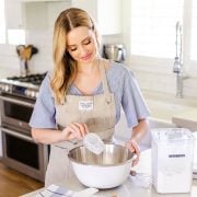 Tessa in the kitchen pouring flour into a bowl.