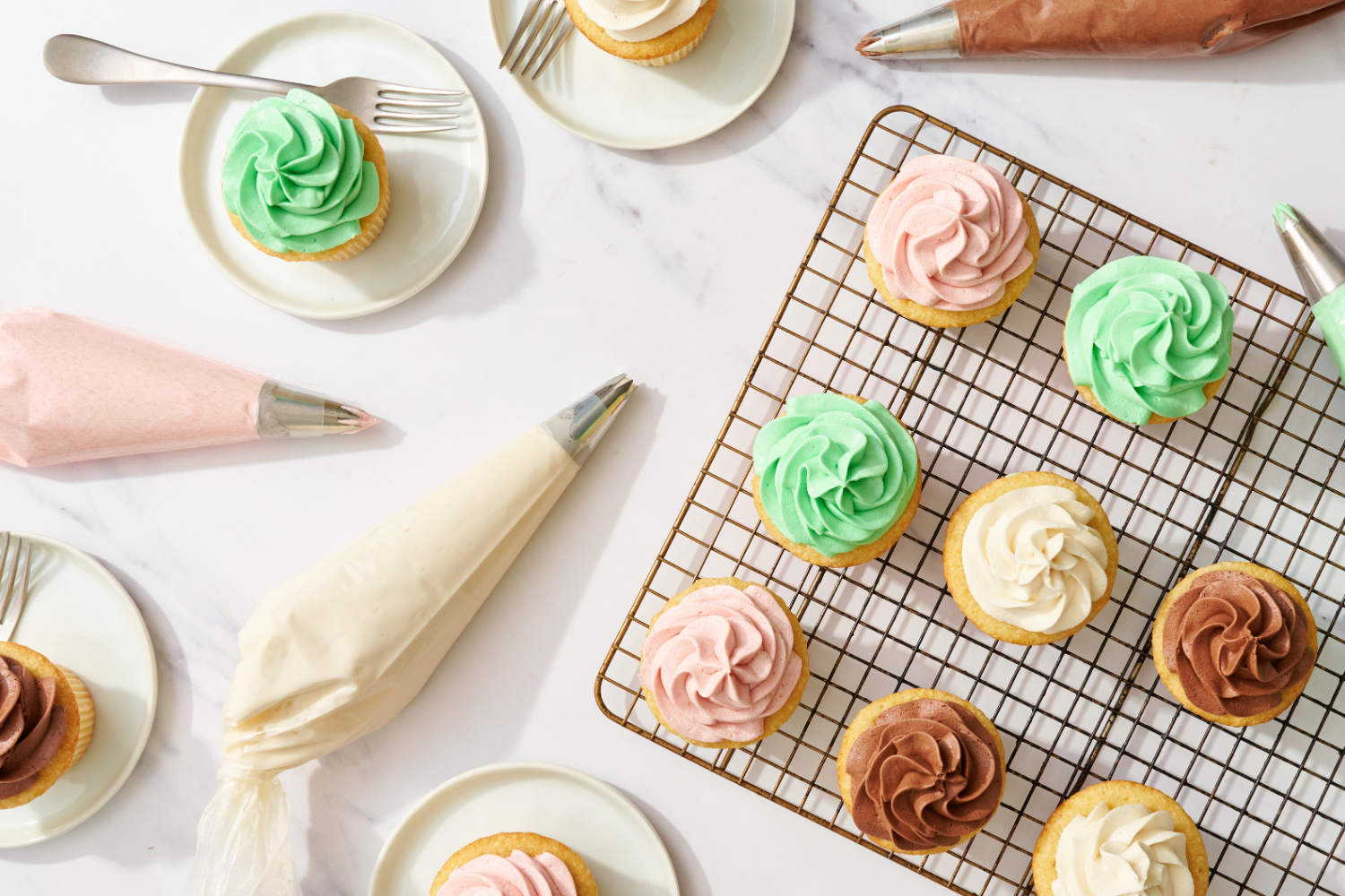 bags of buttercream frosting and cupcakes with piped frosting, ready to serve.