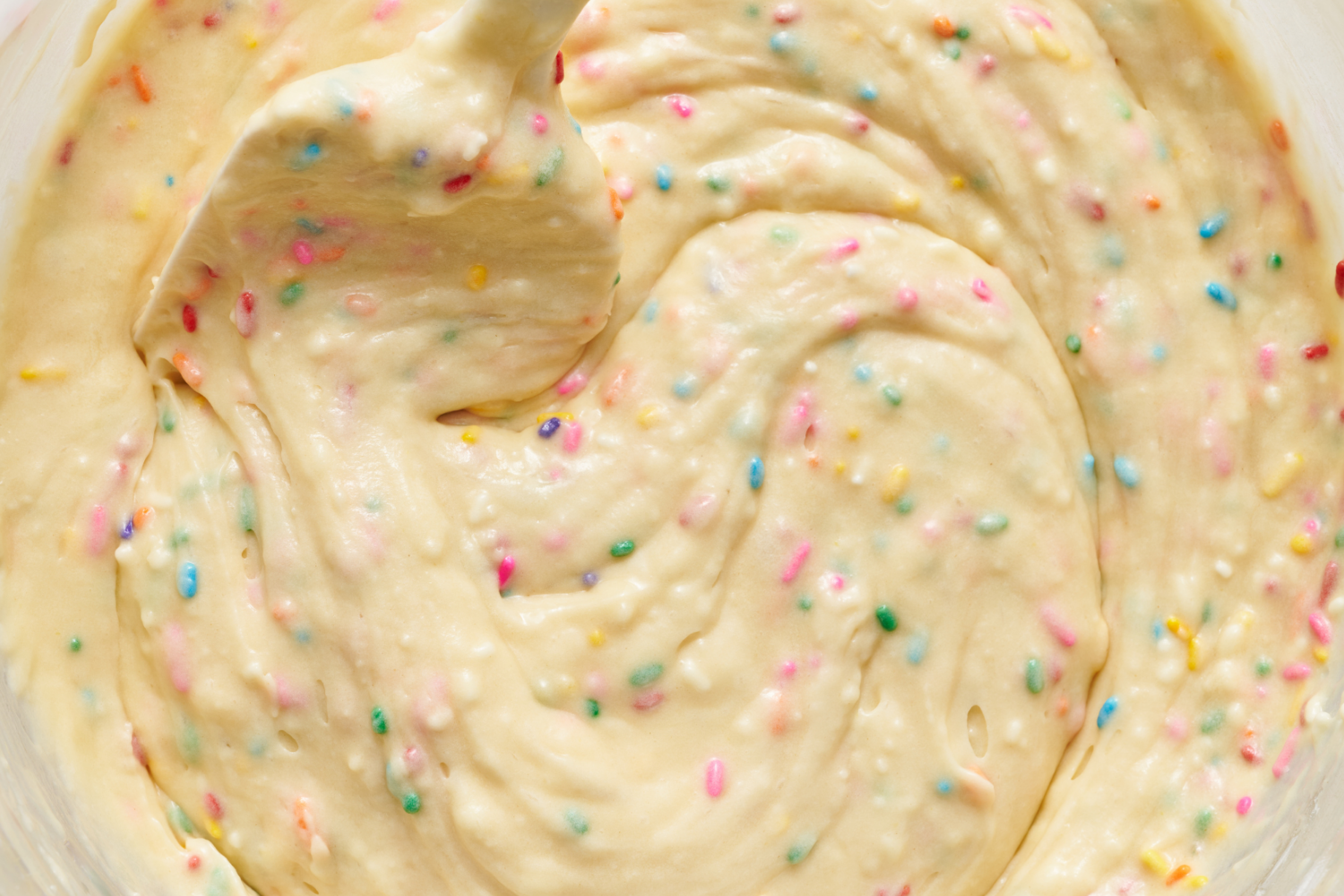 funfetti cake batter in a bowl with a spatula.